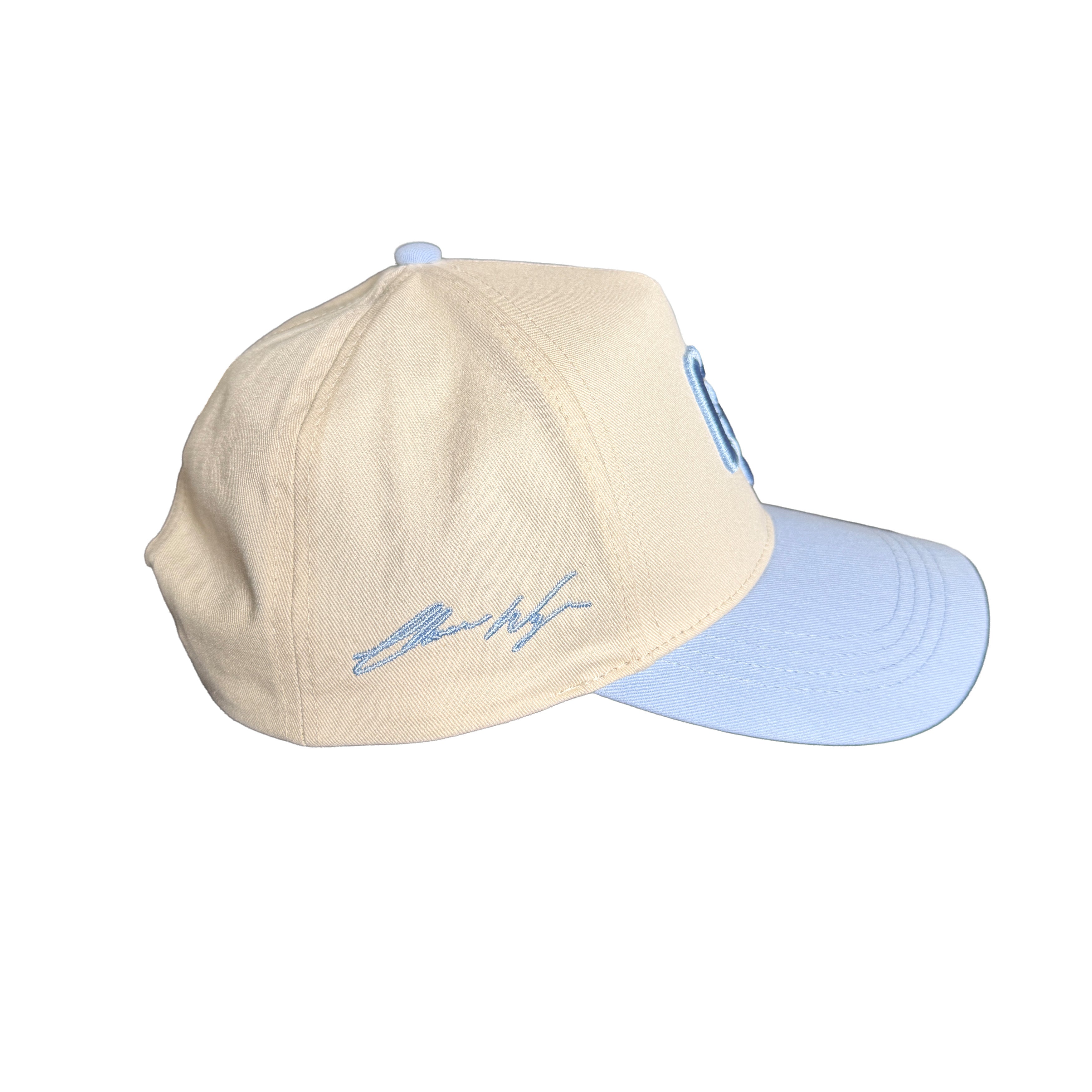 Two-tone beige and light blue cap with a logo on a white background